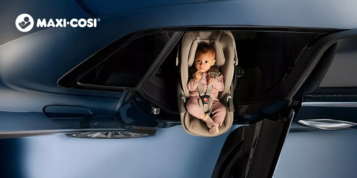 An upside-down banner image of a baby buckled into a beige Maxi-Cosi infant car seat inside a dark vehicle, with the Maxi-Cosi logo on the left.